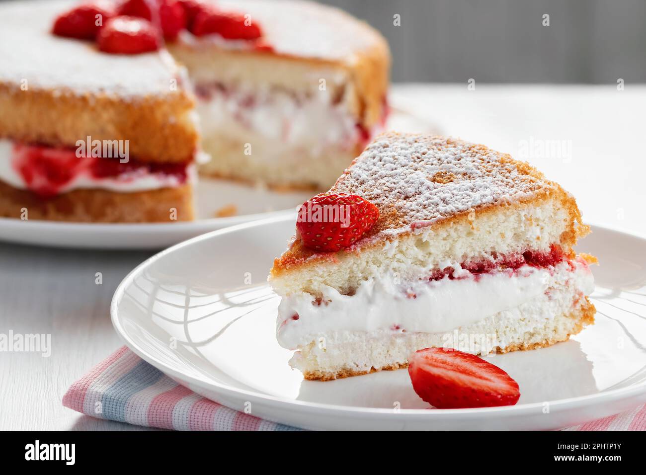 Fetta di torta Victoria biscotto con panna montata, marmellata e fragole fresche. Foto Stock