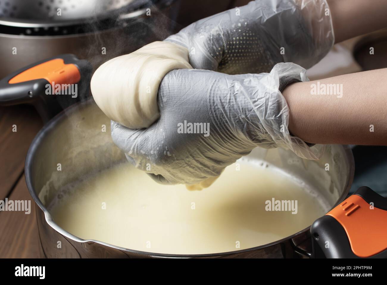 Produzione di mozzarella. Estrarre il coagulo di formaggio dopo il riscaldamento nel siero di latte. Foto Stock