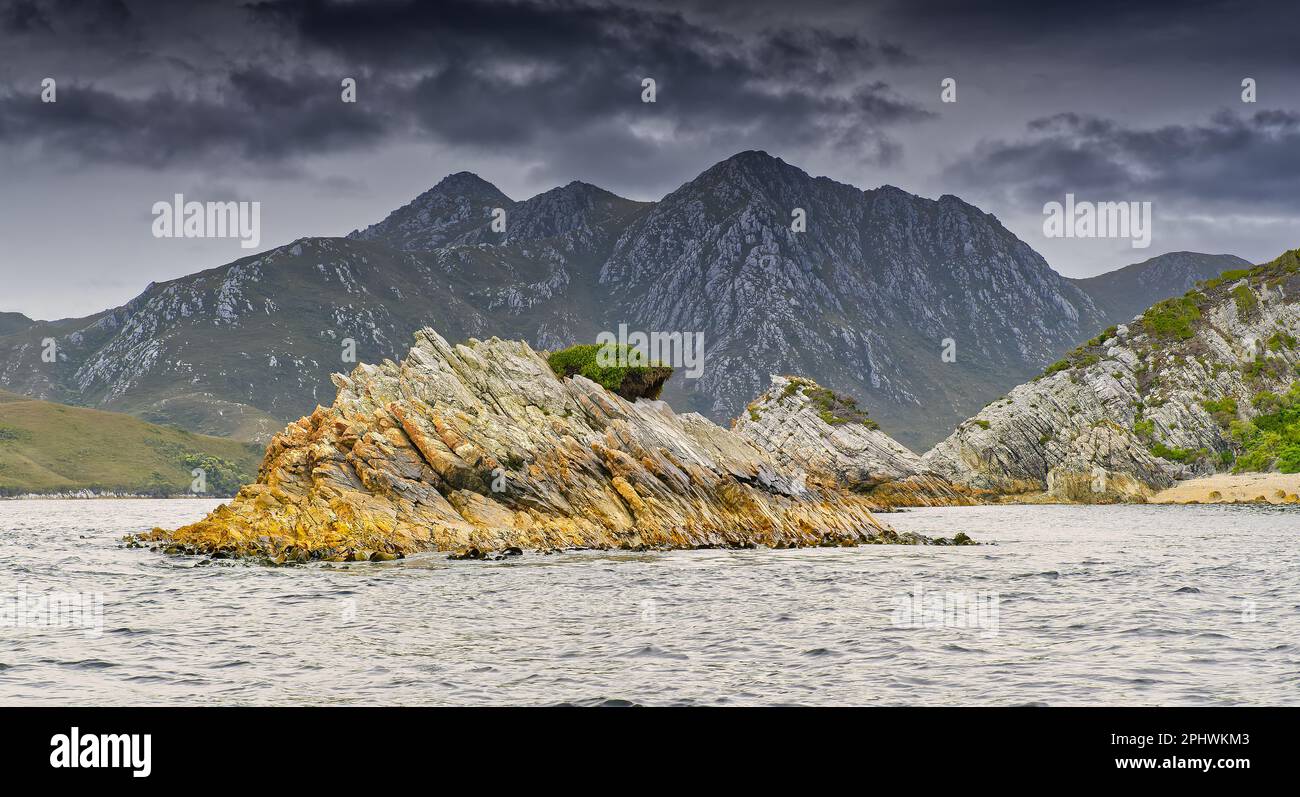 Isolotti rocciosi e cataste nell'oceano a Port Davey North Passage, Bathurst Harbour, South West National Park, Tasmania, Australia Foto Stock