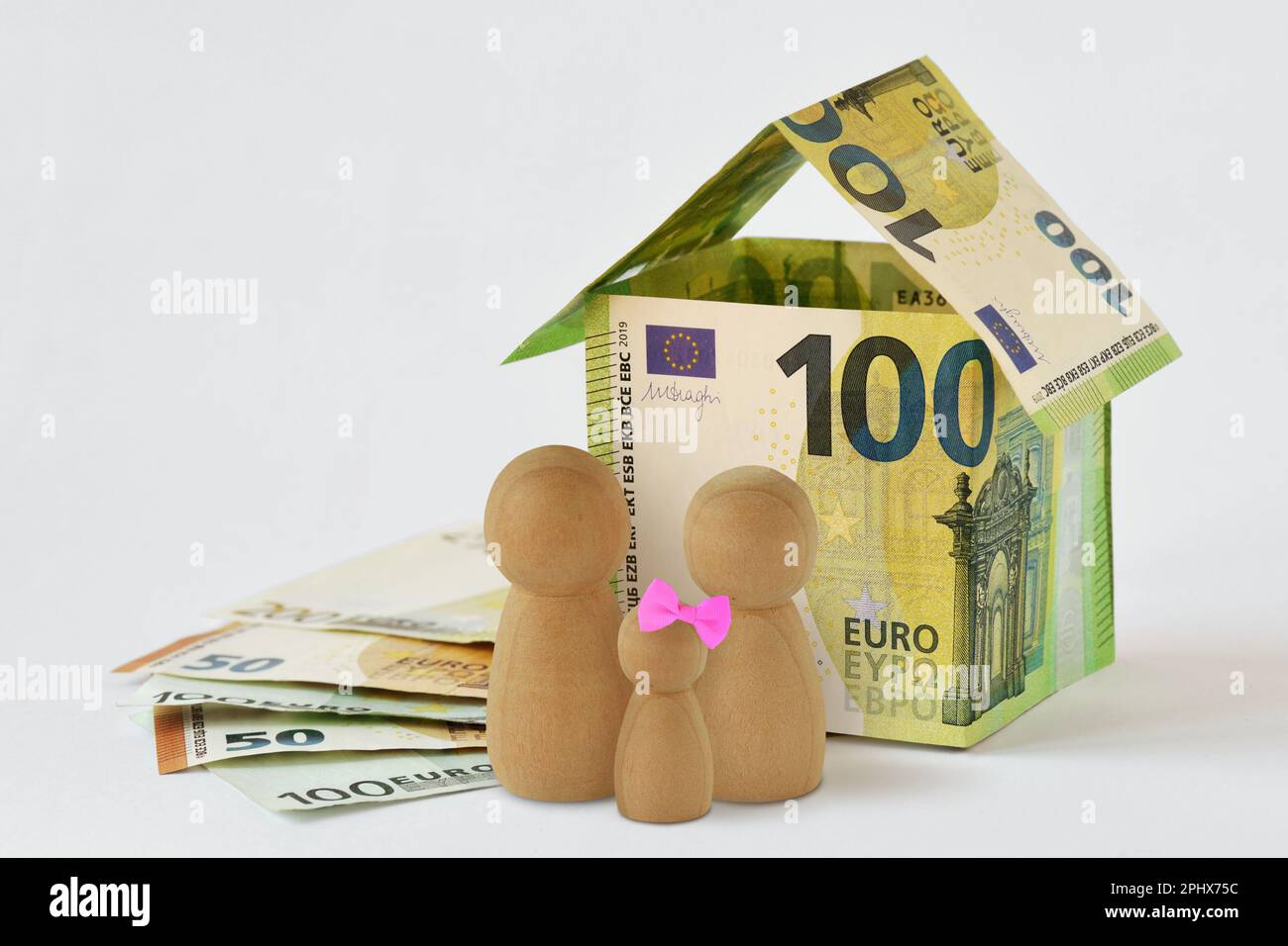 Casa fatta di banconote in euro e pedina di legno su sfondo bianco - concetto di famiglia, casa e protezione finanziaria Foto Stock