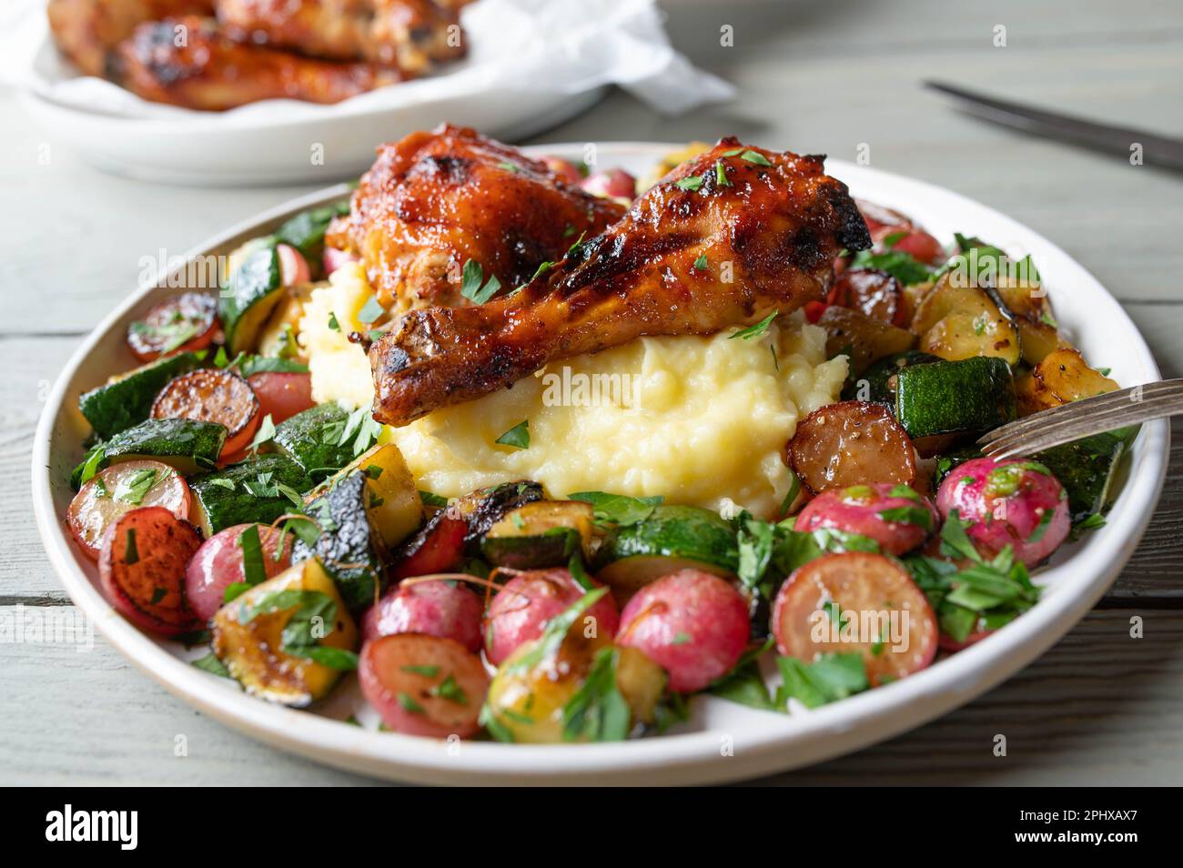 Verdure arrosto con bacchette di pollo smaltate e purè di patate su un piatto Foto Stock