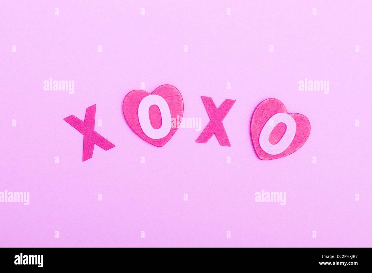 L'iscrizione xo xo da lettere di legno su sfondo rosa. Il concetto di giorno di San Valentino, amore, datazione e matrimonio. Simbolo del bacio. piatto, minim Foto Stock