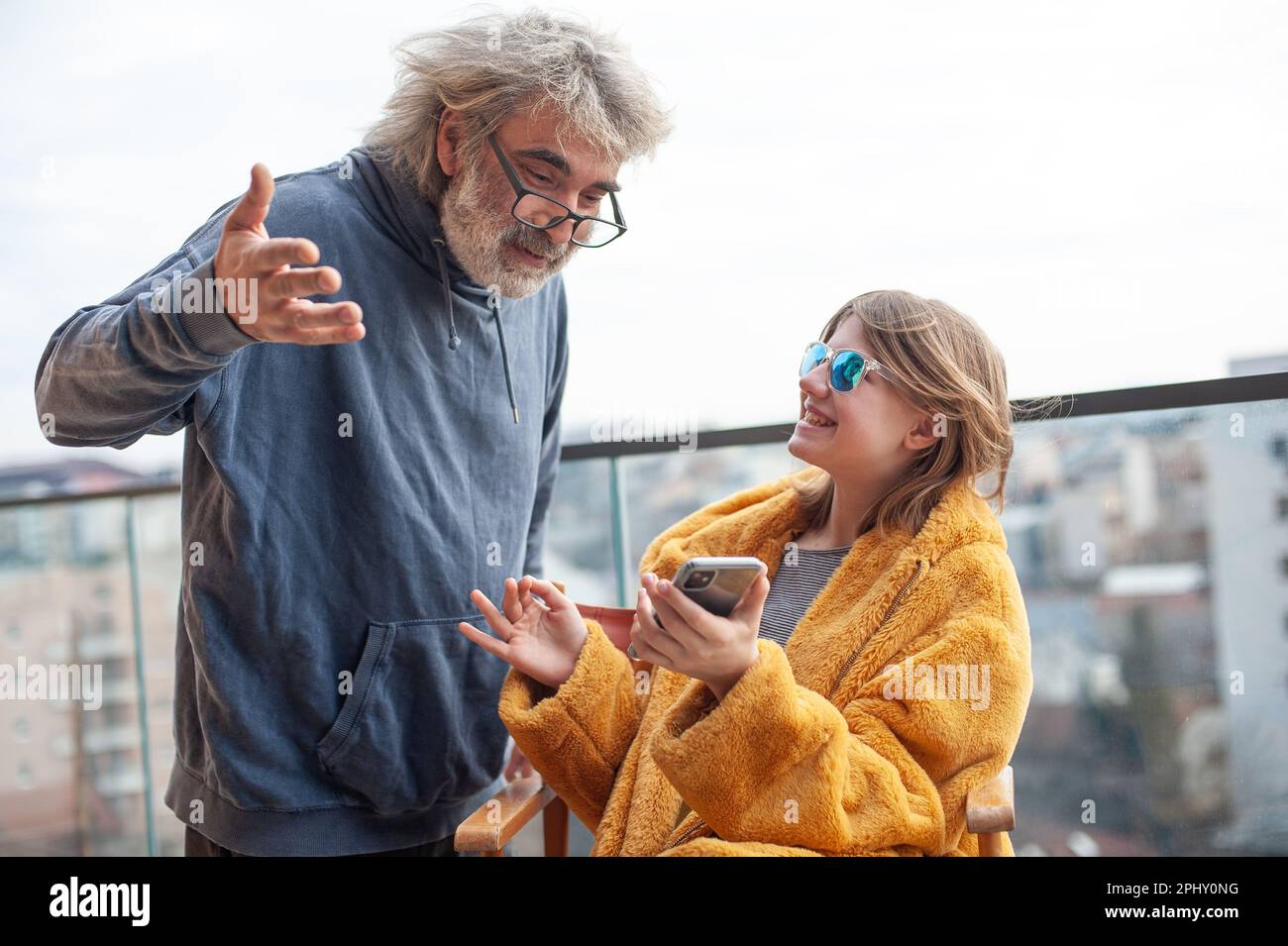 Famiglia felice, padre e figlia utilizzano il telefono sulla terrazza del solitario. Ridono e si divertono. Foto Stock
