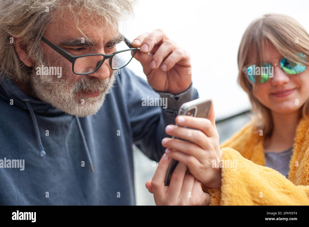 Famiglia felice, padre e figlia utilizzano il telefono sulla terrazza del solitario. Ridono e si divertono. Foto Stock