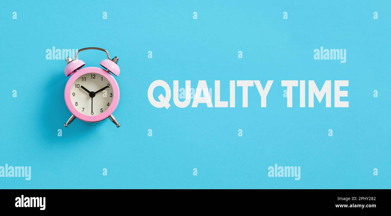 Trascorrere tempo di qualità. Prestare la massima attenzione a qualcuno. Sveglia rosa su sfondo blu con l'ora della qualità del messaggio. Foto Stock