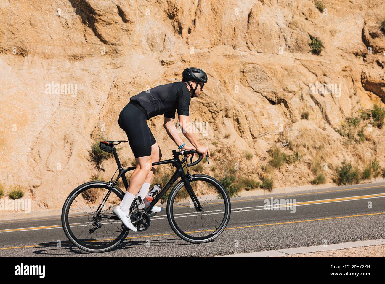 Ciclista maschile sulla sua bici da strada facendo intenso allenamento su una strada vuota Foto Stock