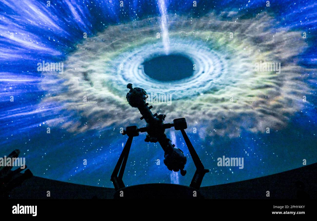 PRODUZIONE - 27 marzo 2023, Sassonia-Anhalt, Halle (Saale): La proiezione di una galassia è visibile dietro il proiettore nella sala stellata del planetario. Dopo circa quattro anni di costruzione, il Planetario Halle viene aperto all'interno delle mura dello storico gasometro con un programma festivo. Il pezzo centrale è la sala stellata con un diametro di dodici metri, un'altezza di otto metri e spazio per 110 persone. L'attrezzatura tecnica permette una vista panoramica a 360 gradi del mondo delle stelle. I fondi per i costi di costruzione di 21 milioni di euro sono stati esclusivamente a carico del re alluvione Foto Stock