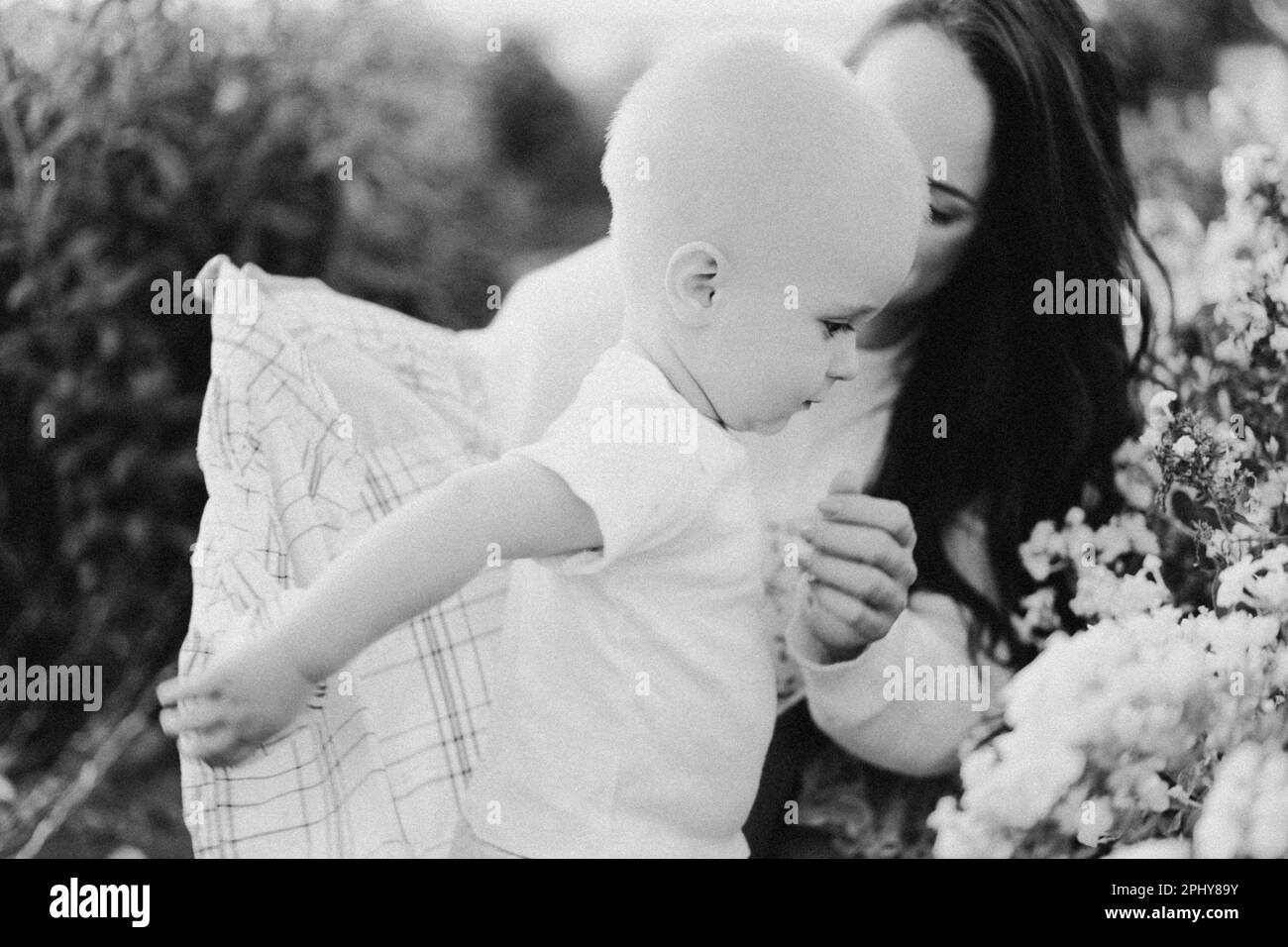 Donna che gioca con il bambino in una serra con fiori Foto Stock