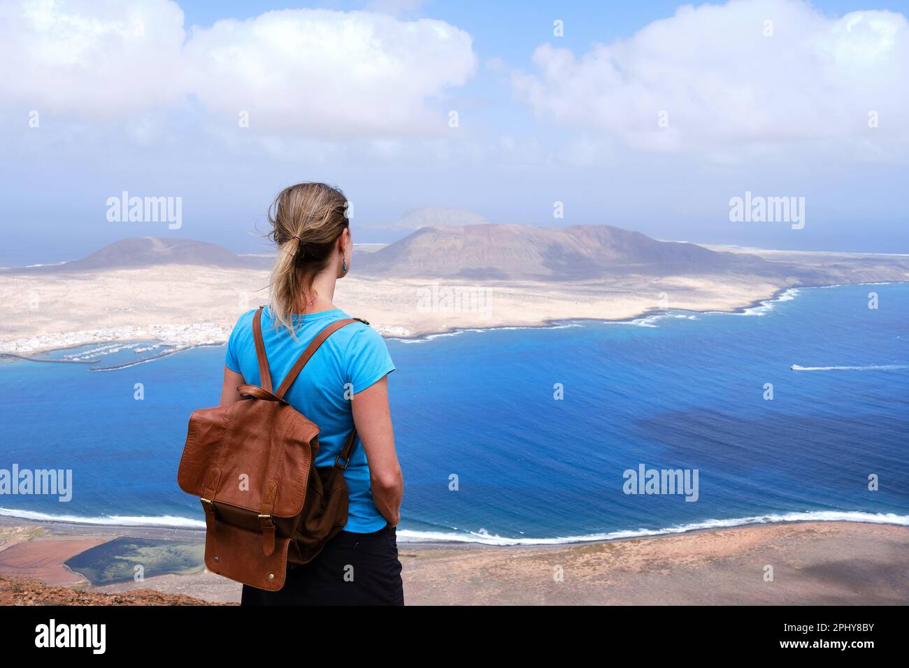 Vista posteriore di una donna che ammira l'isola di la Graciosa a Lanzarote. Isole Canarie Foto Stock