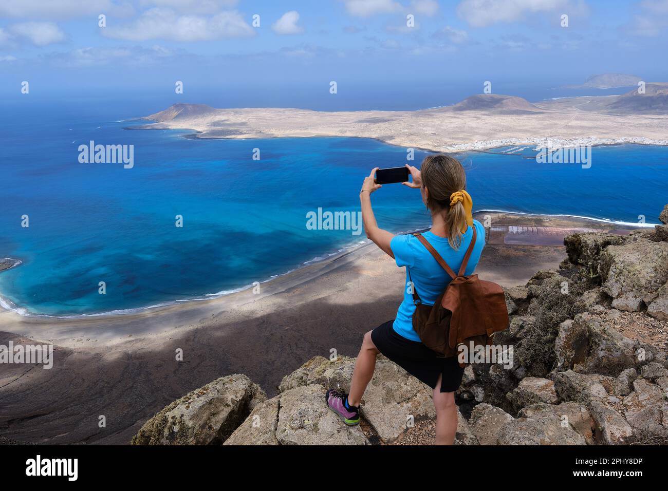 Una donna escursionista fotografando con il suo smartphone dalla cima di una collina la Graciosa Island. Isole Canarie Foto Stock