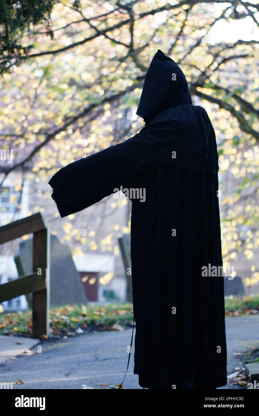 Uno scatto verticale di una figura scheletrica in un lungo, scuro vestito e cappuccio, puntando Foto Stock
