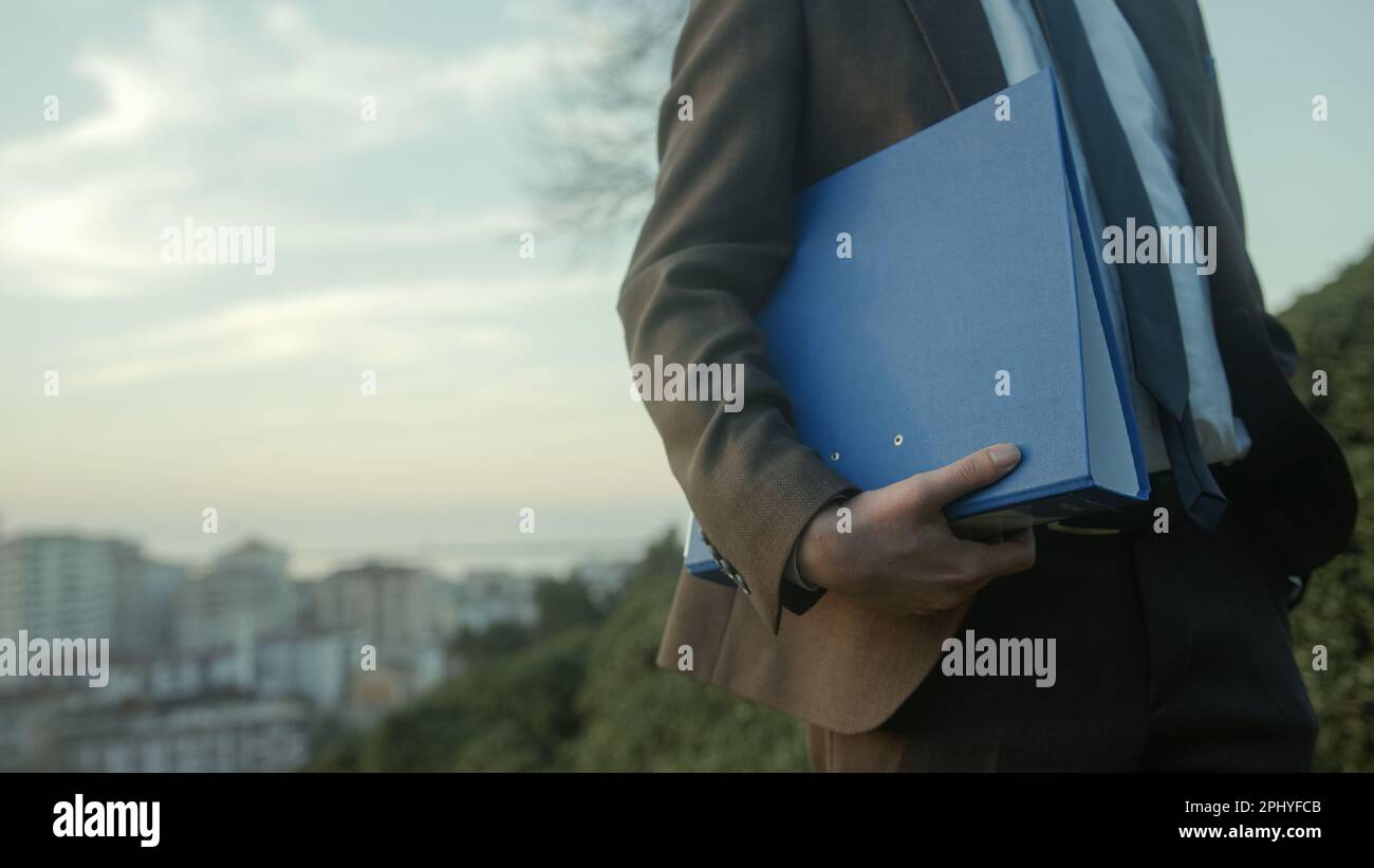 Wide Shot di uomo d'affari in Suit Holding Blue Folder Foto Stock