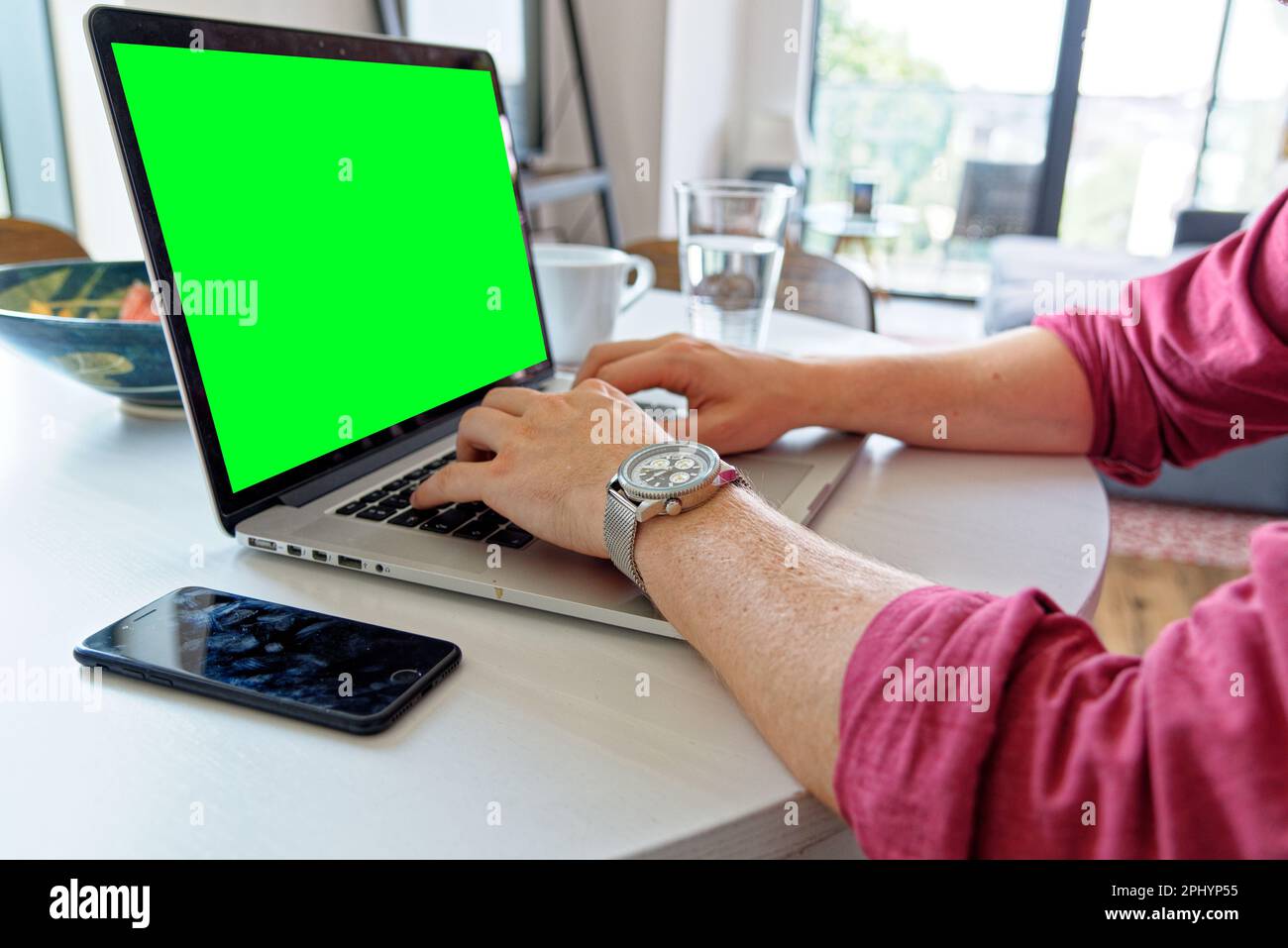 Giovane uomo professionista che utilizza un computer portatile con schermo verde - indossando un orologio di moda. Lavoro da casa - Londra, Regno Unito, 1st giugno 2019 Foto Stock