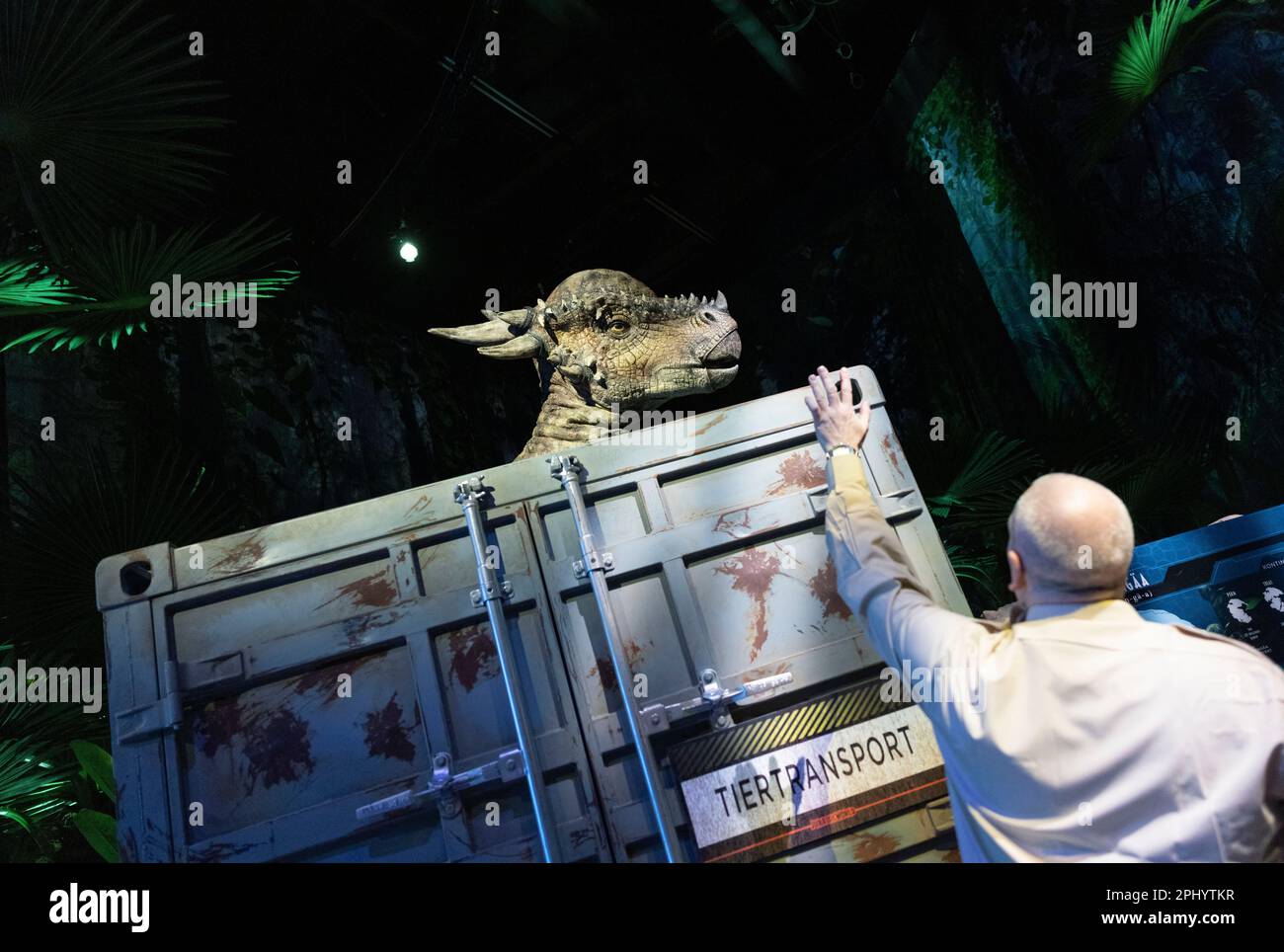 Colonia, Germania. 30th Mar, 2023. Uno Stygimoloch, noto anche come 'Stiggy', può essere visto con il guardiano del parco Thomas nel 'Jurassic World: The Exhibition' all'Odysseum. In una nuova mostra, potrai guardare e accarezzare i dinosauri dei film di successo del "Jurassic World". Credit: Thomas Banneyer/dpa/Alamy Live News Foto Stock