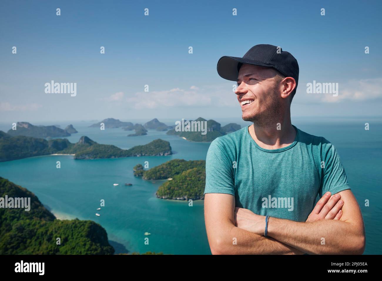 Ritratto di ridere uomo in collina contro un gruppo di isole tropicali in mare, Thailandia Foto Stock