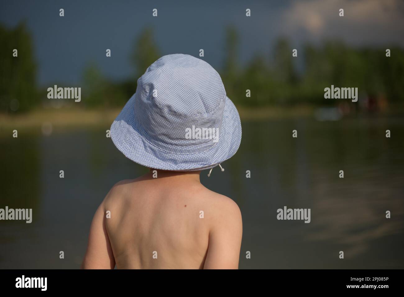 Un bambino in piedi con la schiena in un cappello in acqua e guardando in lontananza. Un ragazzo di quattro anni, Polonia, Europa Foto Stock