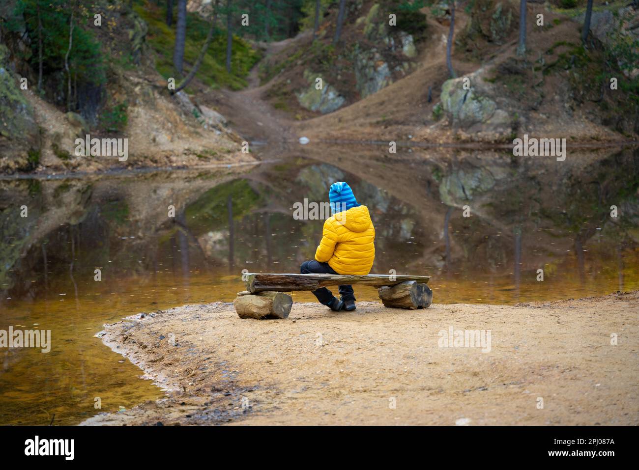 Il bambino sta riposando su una panchina al bordo del lago nel mezzo della foresta. Montagne polacche Foto Stock