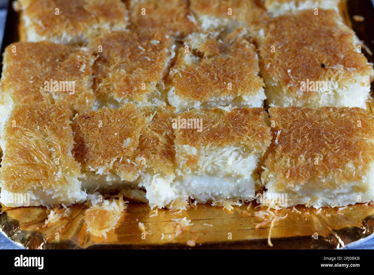 Un tradizionale dessert mediorientale Knafeh Konafa fatto con kataifi di pasta filata, imbevuto in uno sciroppo di miele di zucchero dolce, stratificato con formaggio, o coagulato Foto Stock