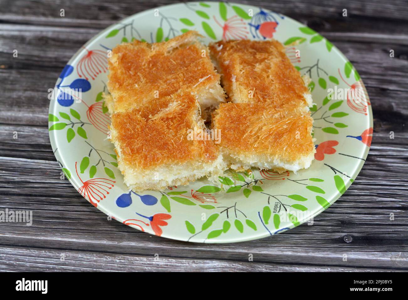 Un tradizionale dessert mediorientale Knafeh Konafa fatto con kataifi di pasta filata, imbevuto in uno sciroppo di miele di zucchero dolce, stratificato con formaggio, o coagulato Foto Stock