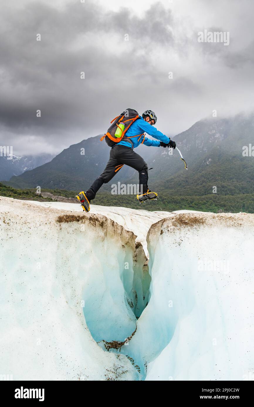 L'escursionista salta su una crevasse di ghiaccio, il ghiacciaio Exploradores nel massiccio di San Valentin, il Parco Nazionale Laguna San Rafael, Puerto Rio Tranquilo, Aysen Foto Stock