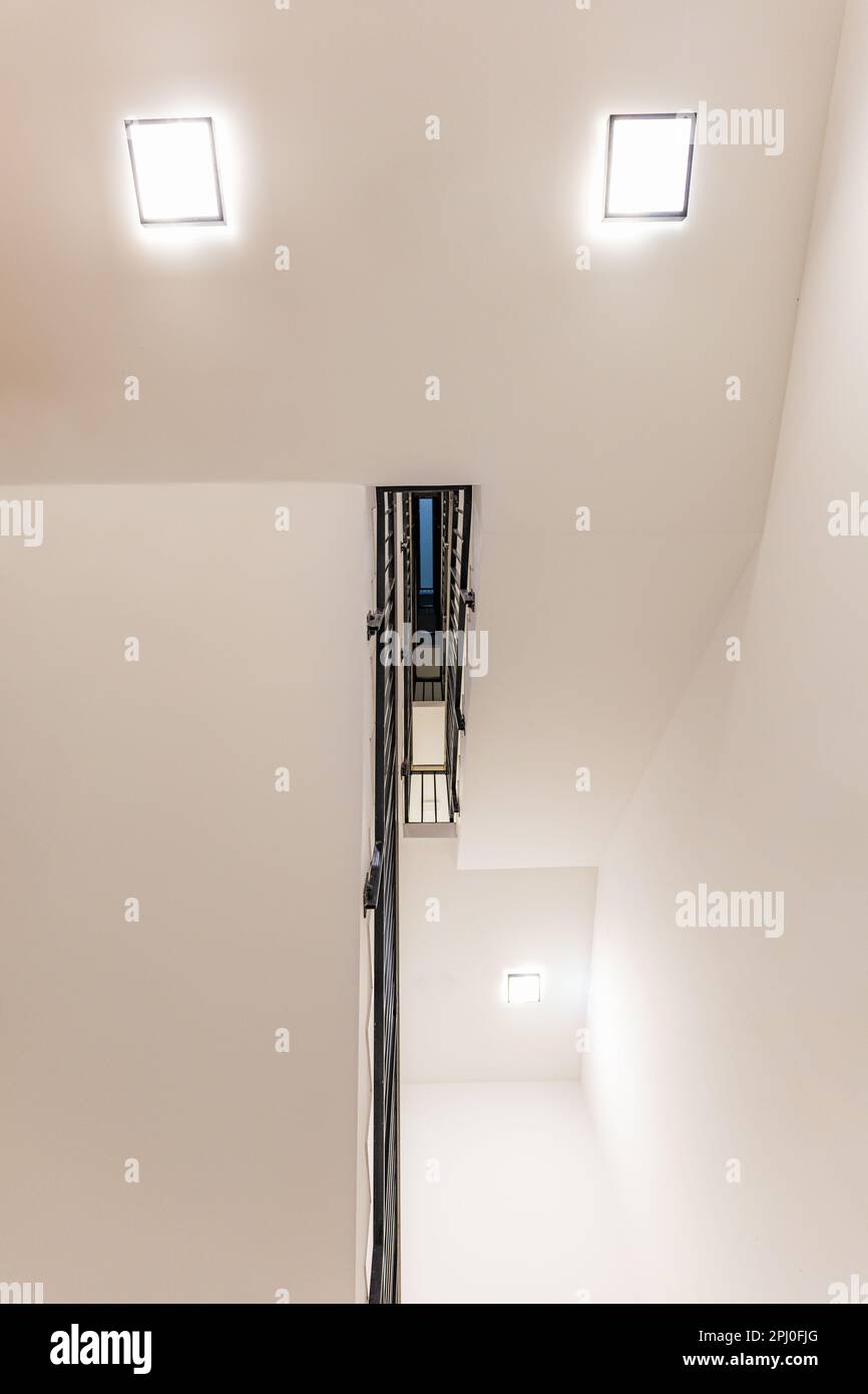 Wroclaw, Polonia - Giugno 2022: Una scala molto luminosa con lampade quadrate e ringhiere in metallo nero visto dal basso Foto Stock