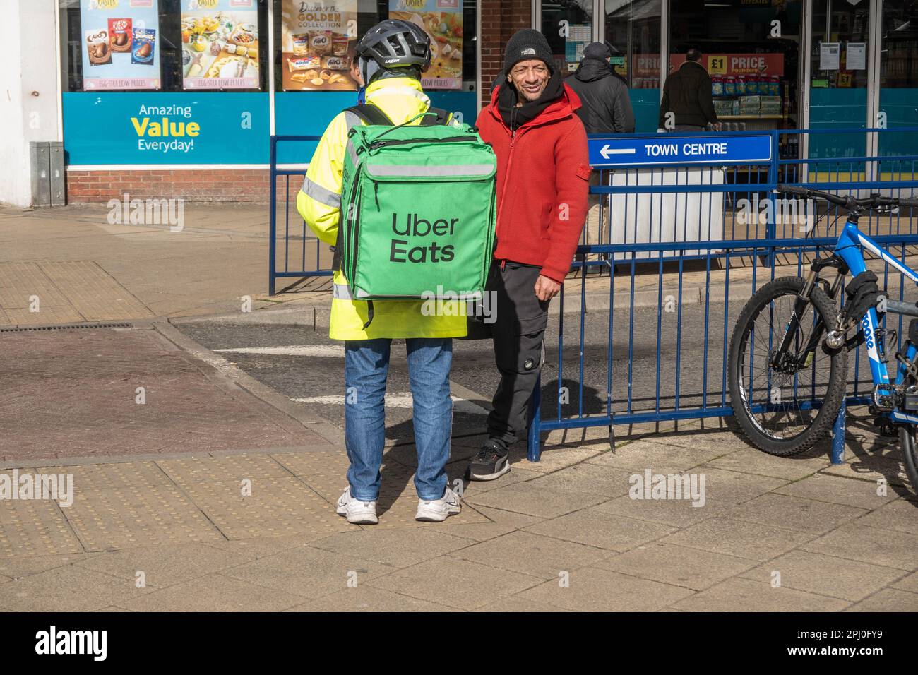 Uber mangia l'uomo di consegna che parla con pedone sul lato della strada a Great Yarmouth Foto Stock