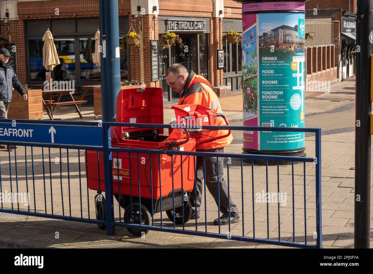 Postman posto di smistamento dal suo carrello a quattro ruote in Great Yarmouth Norfolk Inghilterra UK Foto Stock