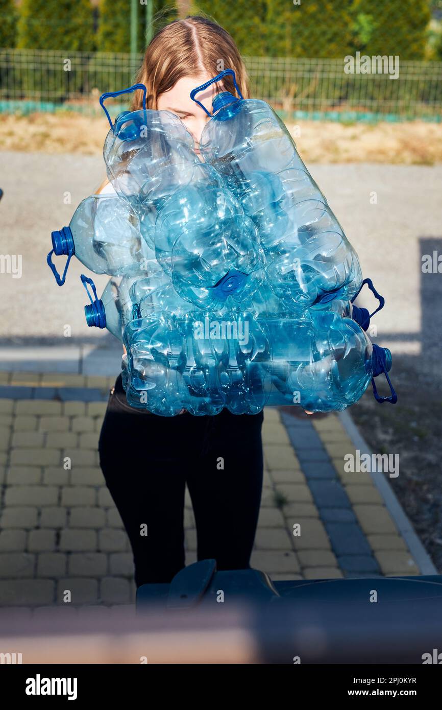 Giovane donna gettando fuori le bottiglie vuote di plastica usate dell'acqua nel cestino. Raccolta dei rifiuti in plastica per il riciclaggio. Concetto di inquinamento plastico e anche Foto Stock