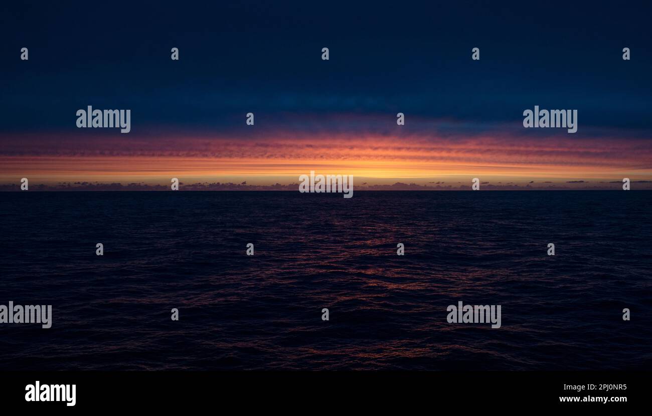 Ultima luce sull'oceano, da una nave mentre attraversiamo il Mare del Nord, il cielo si illuminò di rosso dopo il tramonto, riflettendosi nelle onde scure quando arriva la notte Foto Stock