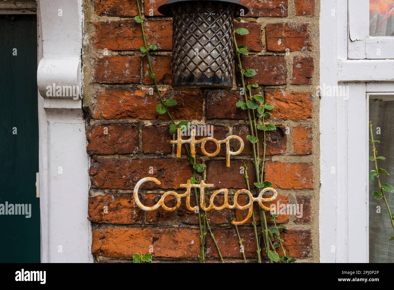 Hop Cottage segno sul muro di mattoni rossi, Farnham, Surrey, Regno Unito Foto Stock