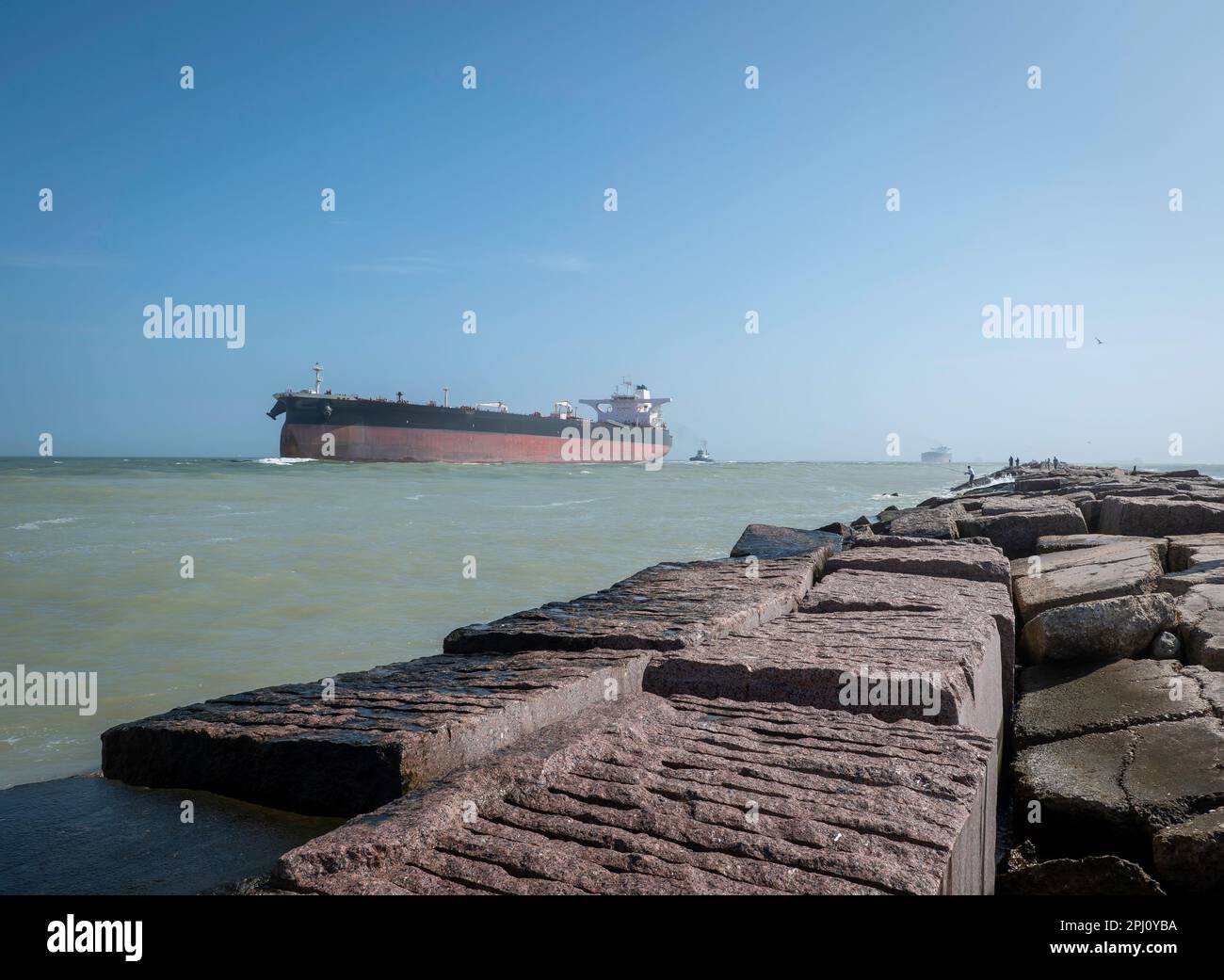 Le grandi rocce di granito del South Jetty a Port Aransas, Texas, e le navi petroliere che si avvicinano dal Golfo del Messico sulle acque della spedizione c Foto Stock