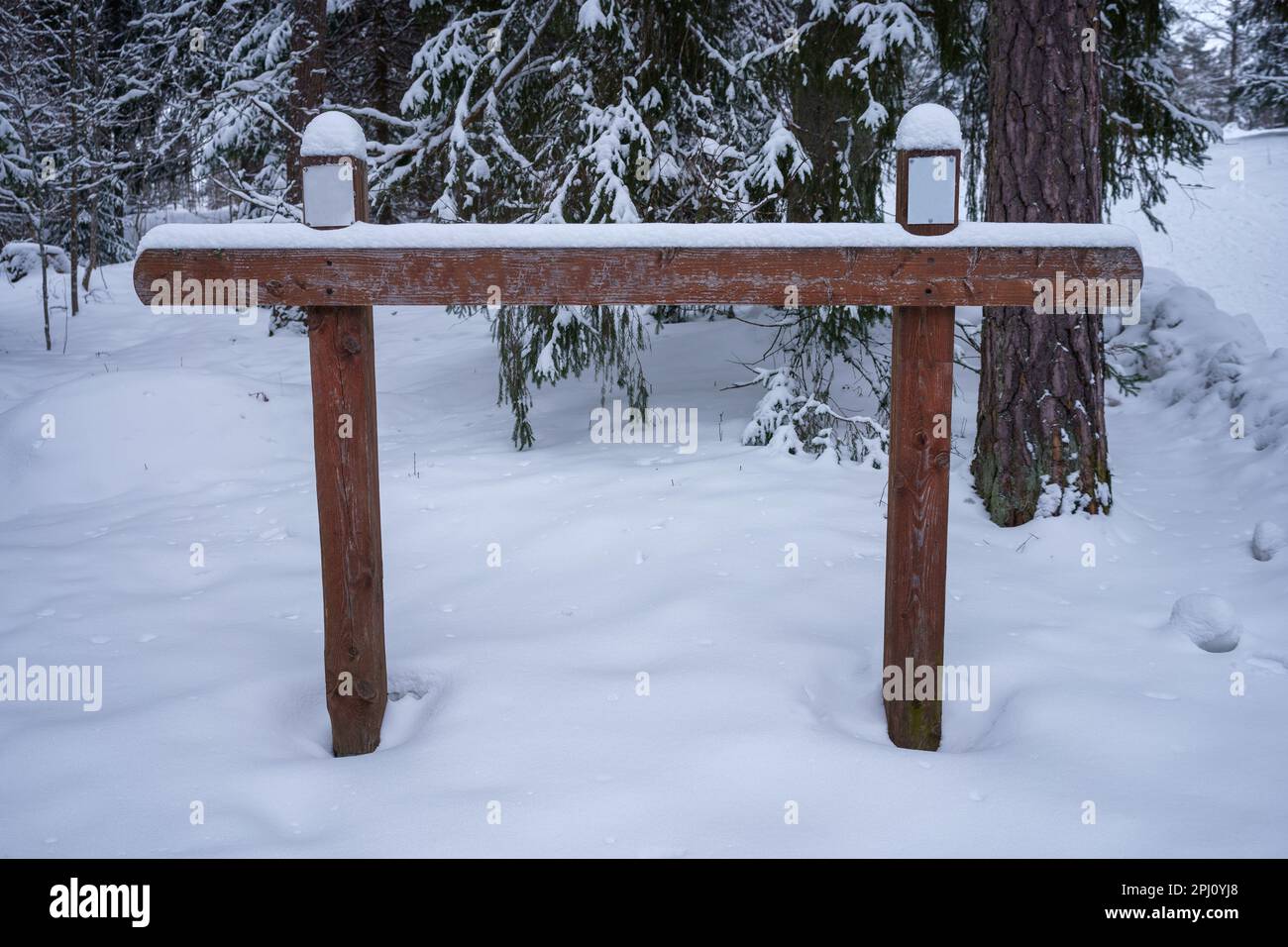Vuoto segno di legno inverno. Coperto di neve con alberi sullo sfondo Foto Stock