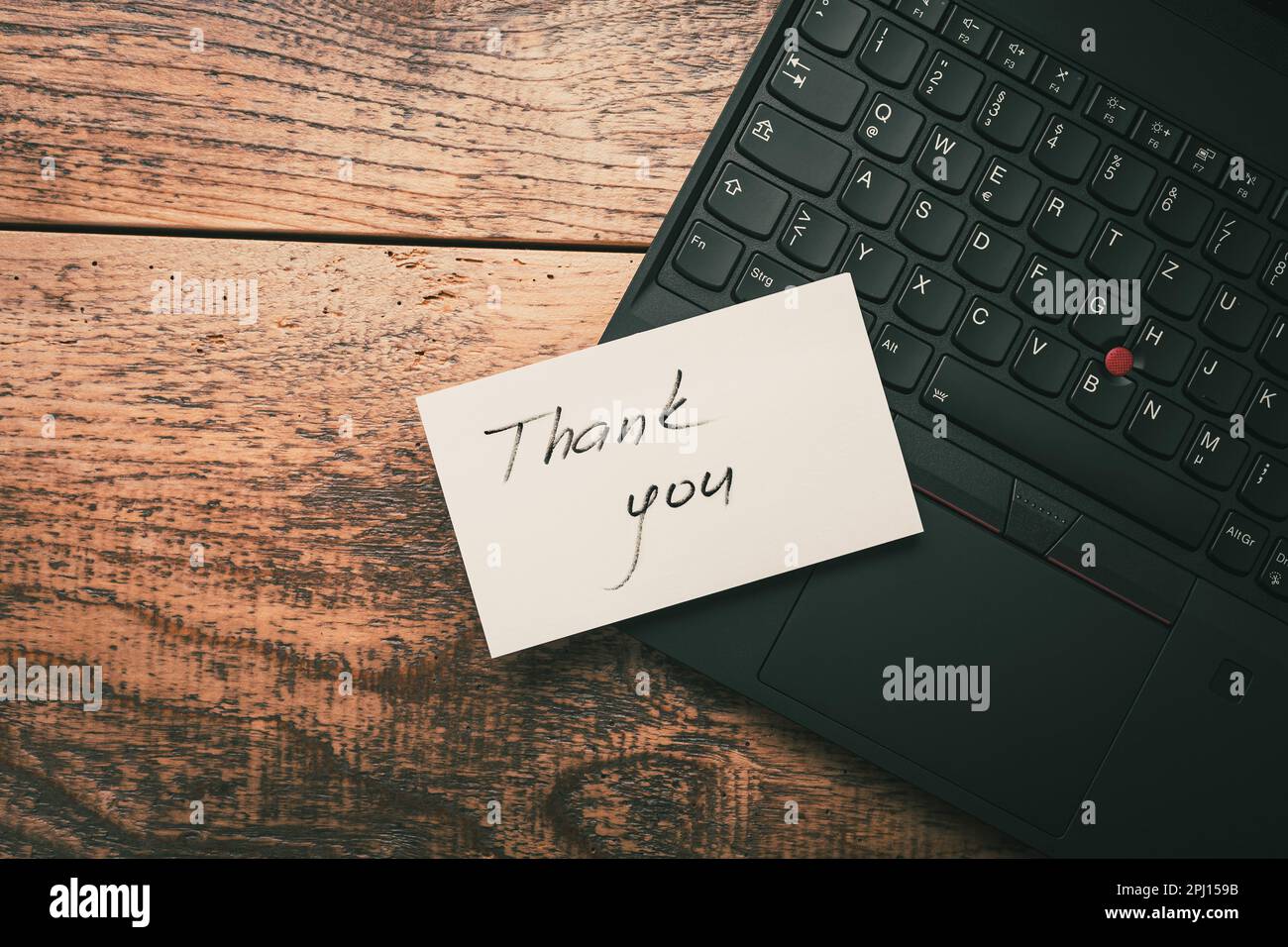 Primo piano del messaggio adesivo di ringraziamento sul laptop su sfondo di legno Foto Stock