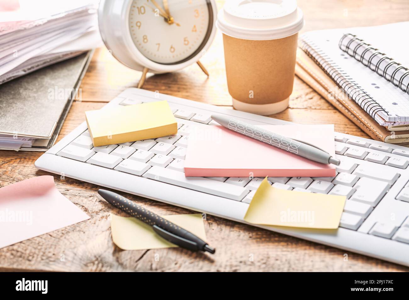 Concetto di gestione del tempo. Composizione con sveglia su tavolo di legno con computer portatile, stazionari e post-it note Foto Stock