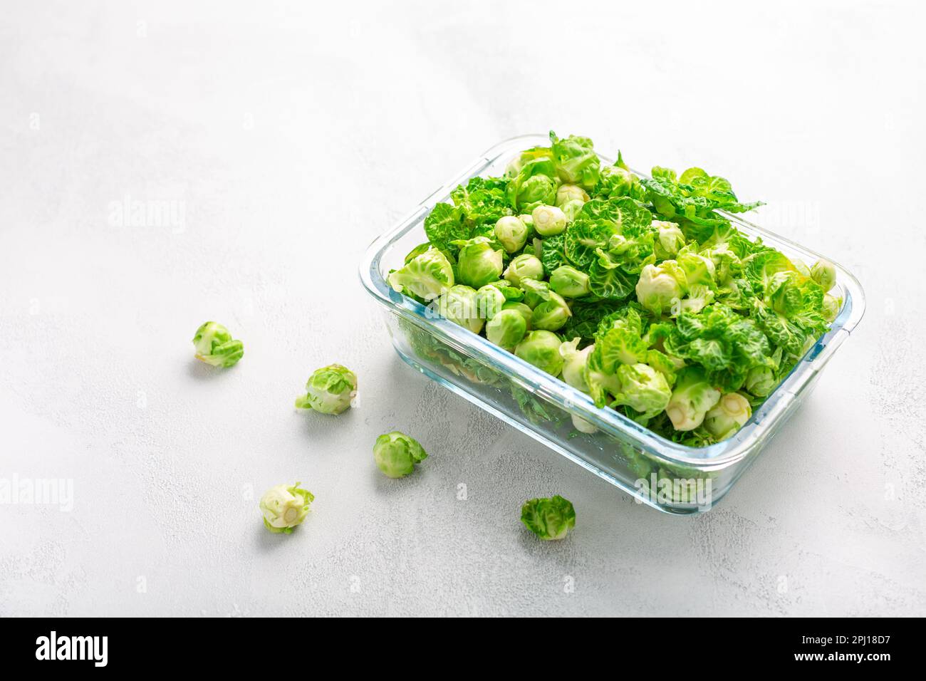 Germogli di bruxelles freschi e verdi e piccoli ortaggi a cappuccio invernali in contenitore di vetro, pronti per il congelamento Foto Stock