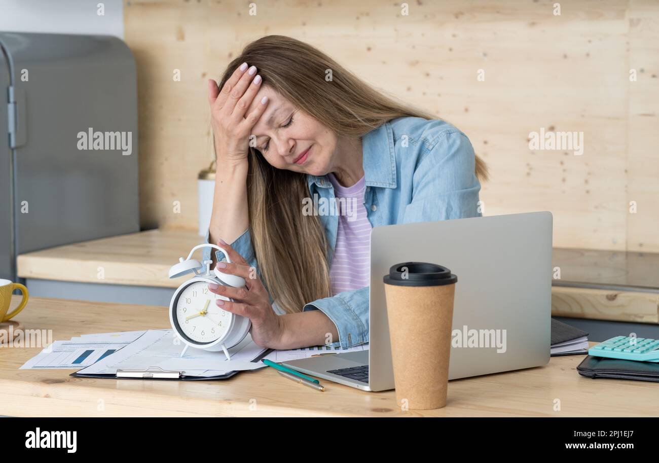 Donna disaccoppiata seduta alla scrivania in ufficio circondata da documenti, Work Life Balance, Work lif Balance Concept Foto Stock