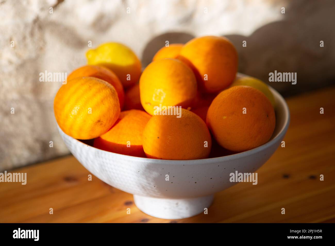 Tomar, Portogallo. 26th Mar, 2023. Arance e limoni si trovano in una ciotola che si trova su un fianco di fronte a un muro di pietra. Credit: Viola Lopes/dpa/Alamy Live News Foto Stock