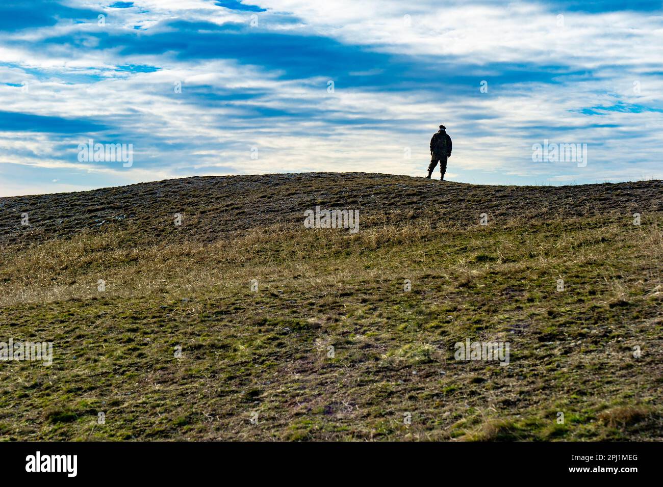 Silhouette di un soldato in piedi su una collina alla luce del sole invernale Foto Stock