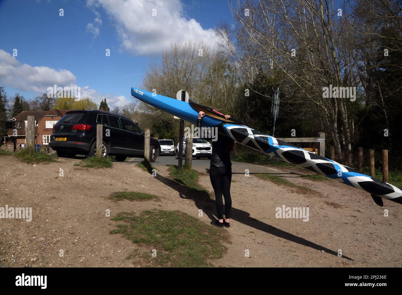 Donna che porta canoa sulle rive del fiume Wey Navigations Surrey Inghilterra Foto Stock