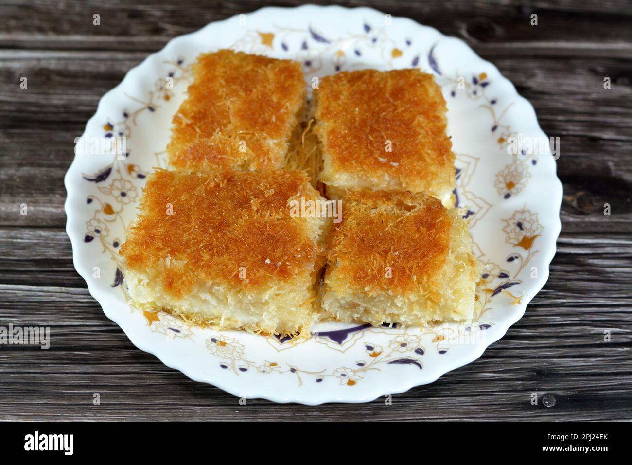 Un tradizionale dessert mediorientale Knafeh Konafa fatto con kataifi di pasta filata, imbevuto in uno sciroppo di miele di zucchero dolce, stratificato con formaggio, o coagulato Foto Stock