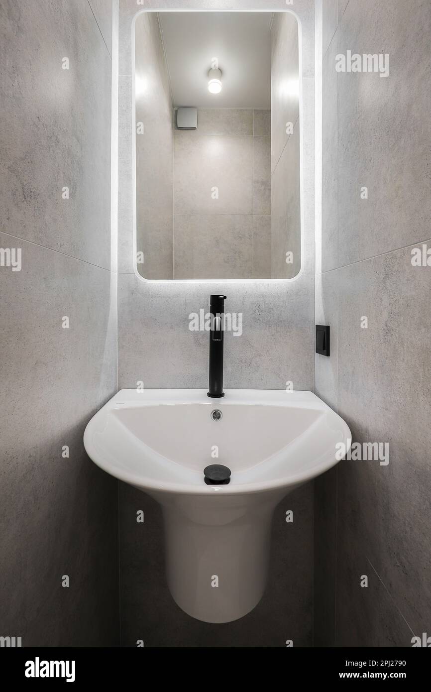 Rubinetto nero con lavabo in ceramica bianca e specchio in bagno Foto Stock Rubinetto nero con lavabo in ceramica bianca e specchio in bagno Foto Stock