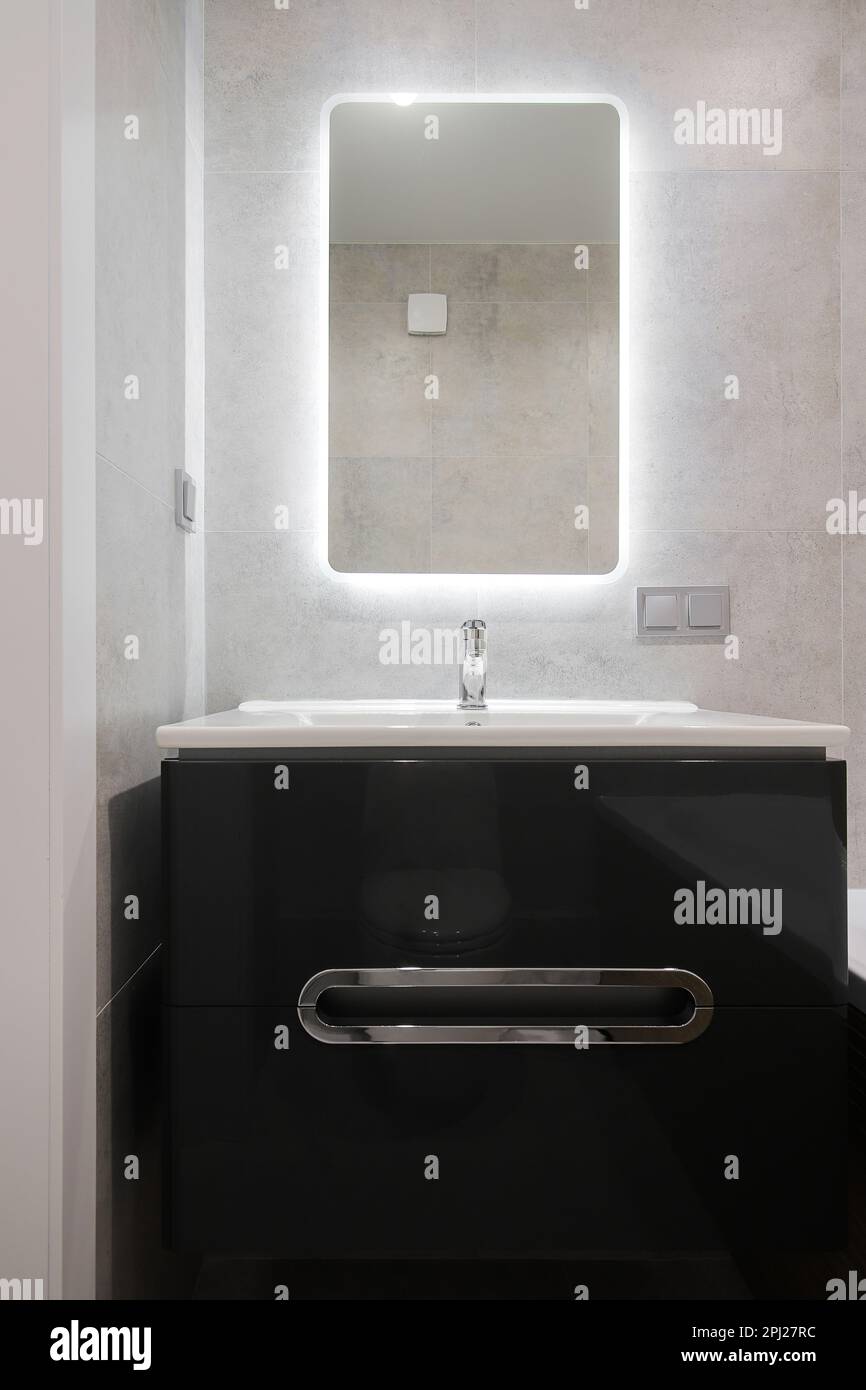 Rubinetto con lavabo in ceramica bianca e specchio in bagno Foto Stock Rubinetto con lavabo in ceramica bianca e specchio in bagno Foto Stock