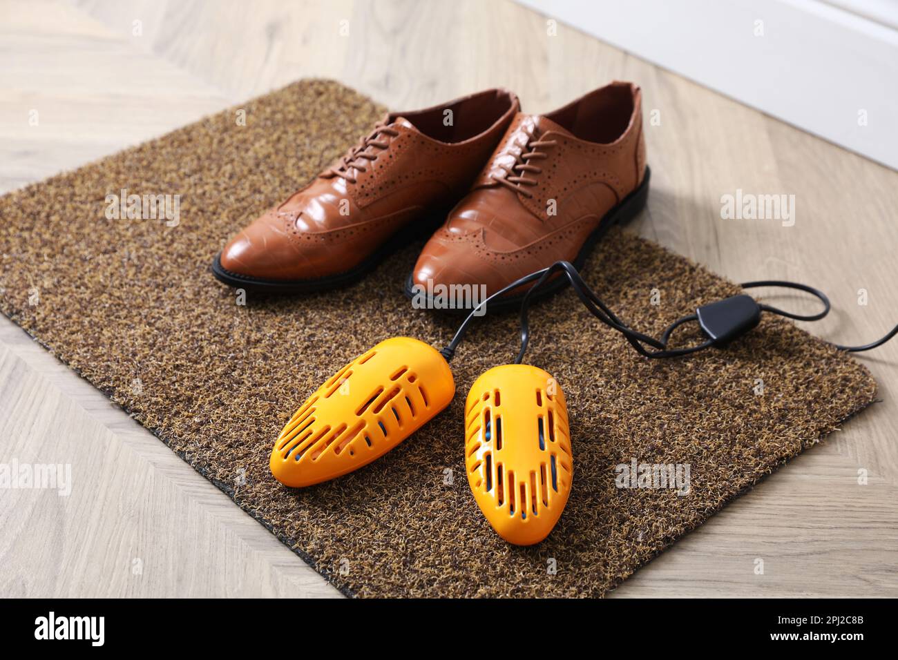 Paio di scarpe eleganti con un moderno asciugabiancheria elettrico sul  tappetino della porta per interni Foto stock - Alamy