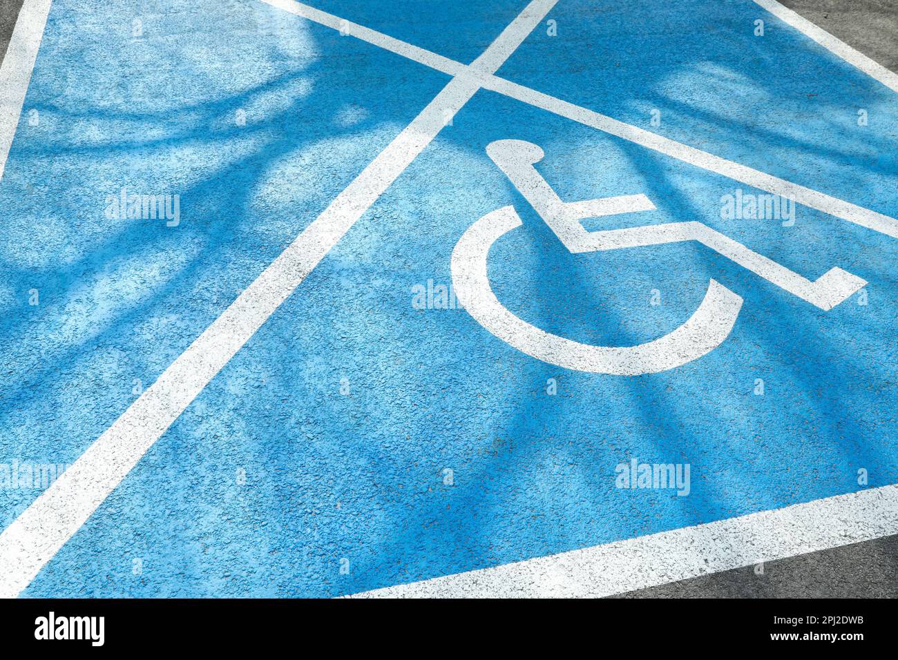 Simbolo della sedia a rotelle su strada asfaltata. Permesso di parcheggio per disabili Foto Stock