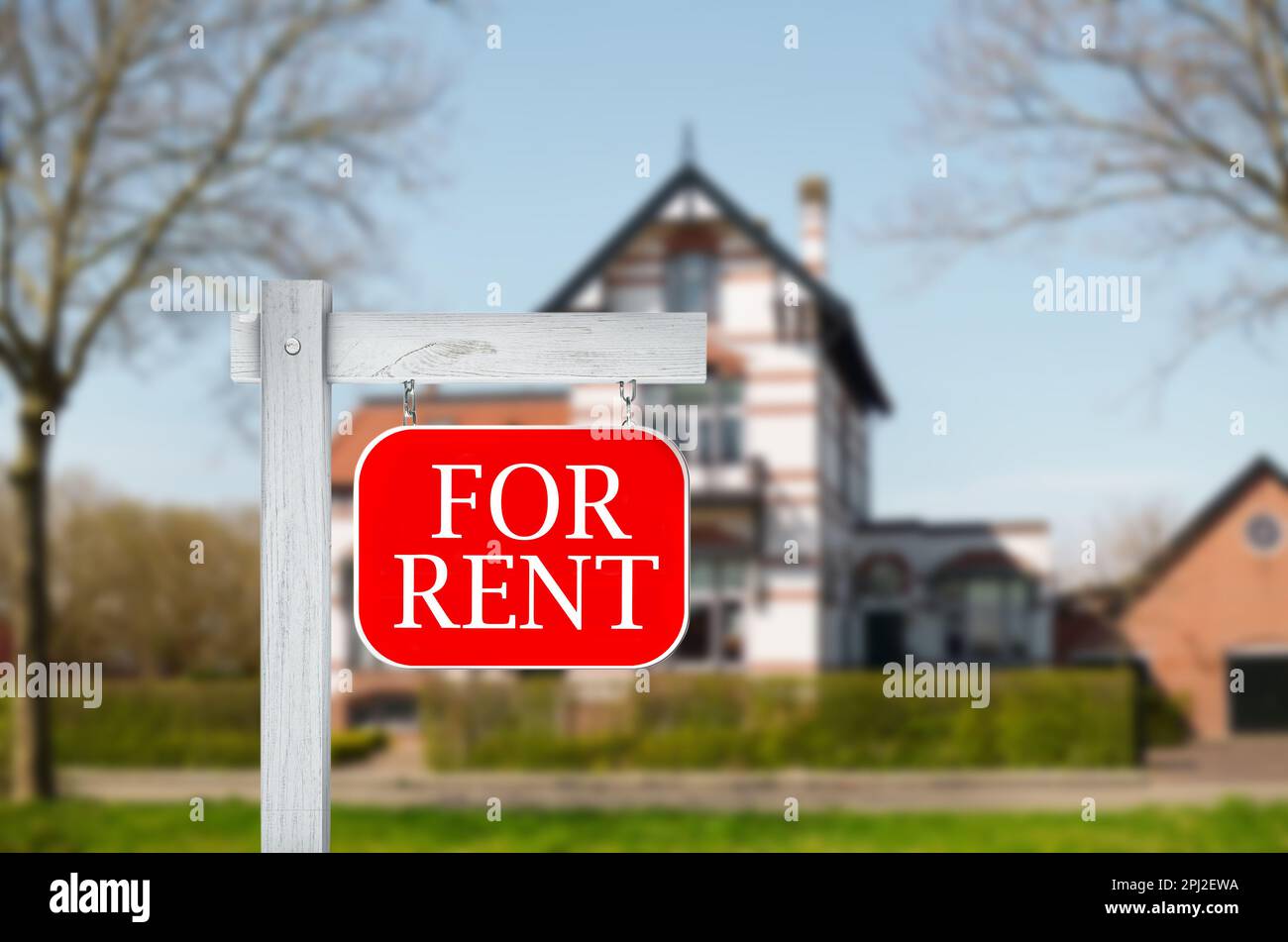 Segno con frase IN AFFITTO e vista offuscata di bella casa Foto Stock