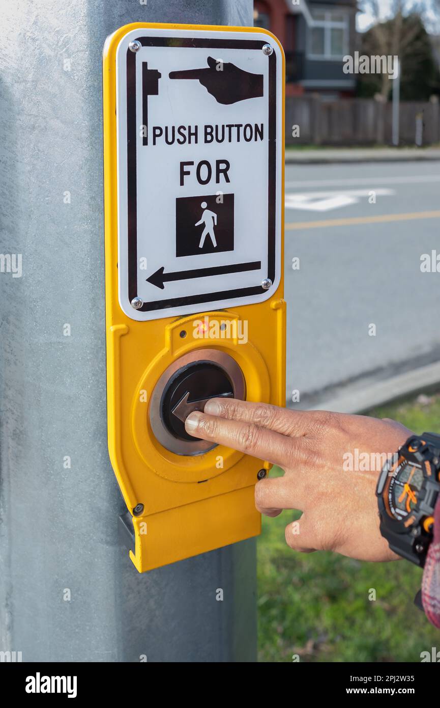 Premere a mano un pulsante al semaforo sull'incrocio pedonale. Premere il pulsante per il semaforo. Il pulsante del meccanismo accende i semafori sul Th Foto Stock