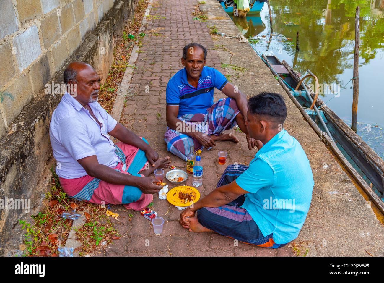 Negombo, Sri Lanka, 13 febbraio 2022: I pescatori locali fanno uno spuntino al canale olandese di Negombo. Foto Stock