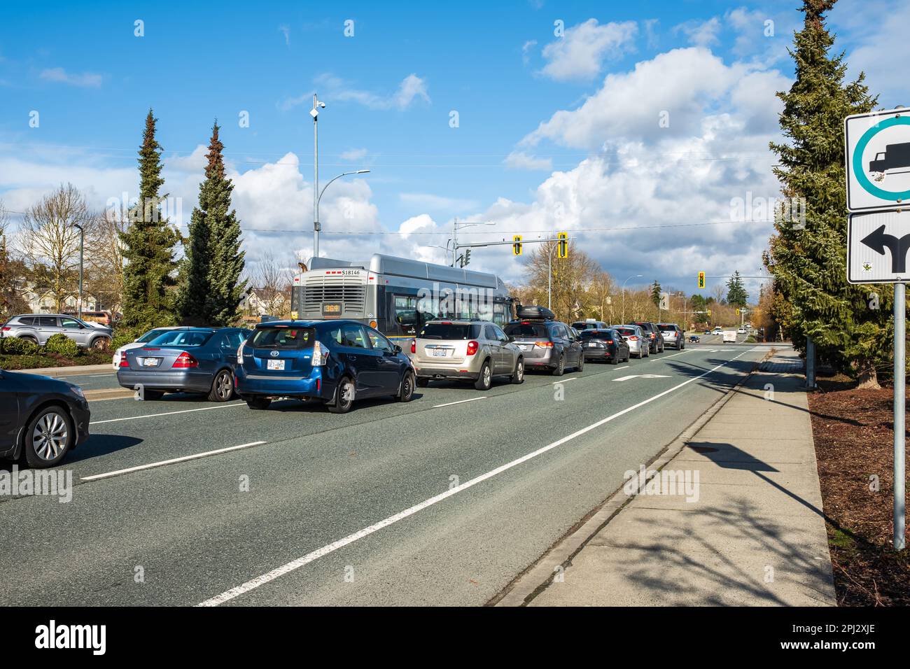 Traffico che attraversa la città. Ingorgo del traffico in strada, le auto si spostano su una strada cittadina in una giornata di sole. Semaforo su un'autostrada in Surrey BC Canada-F. Foto Stock