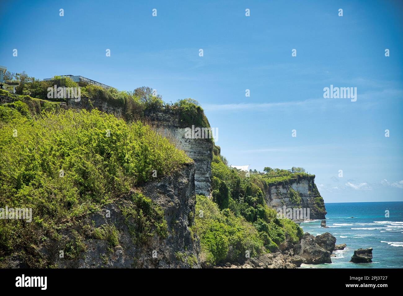 Vista panoramica sulla costa con le sue imponenti scogliere sovrastanti di cespugli dalla spiaggia di Suluban sul Balin in Indonesia. Foto Stock