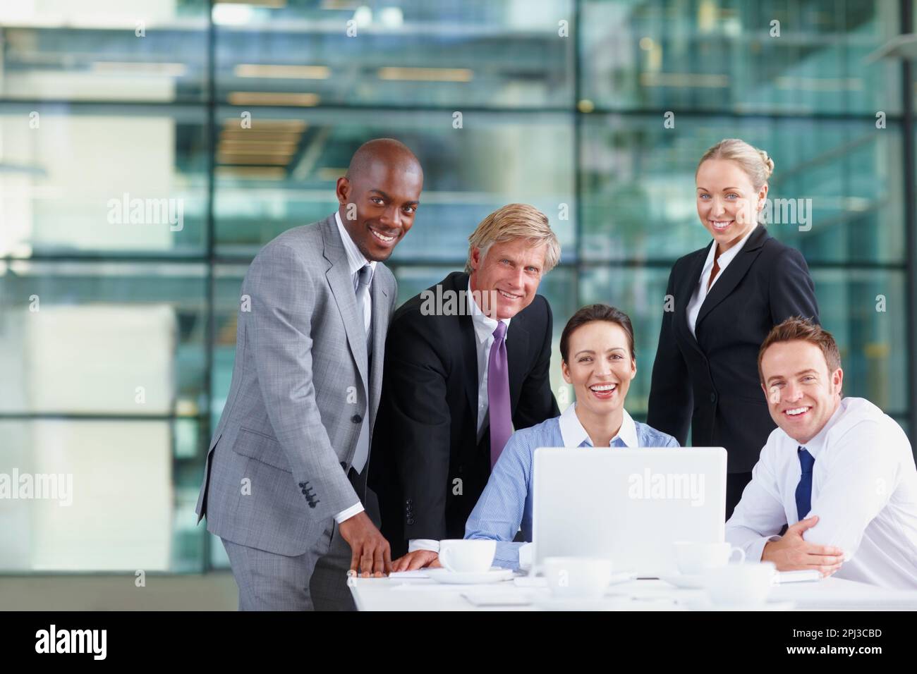 Team aziendale sicuro. Uomini d'affari multietnici di successo sorridenti con il laptop sul tavolo. Foto Stock